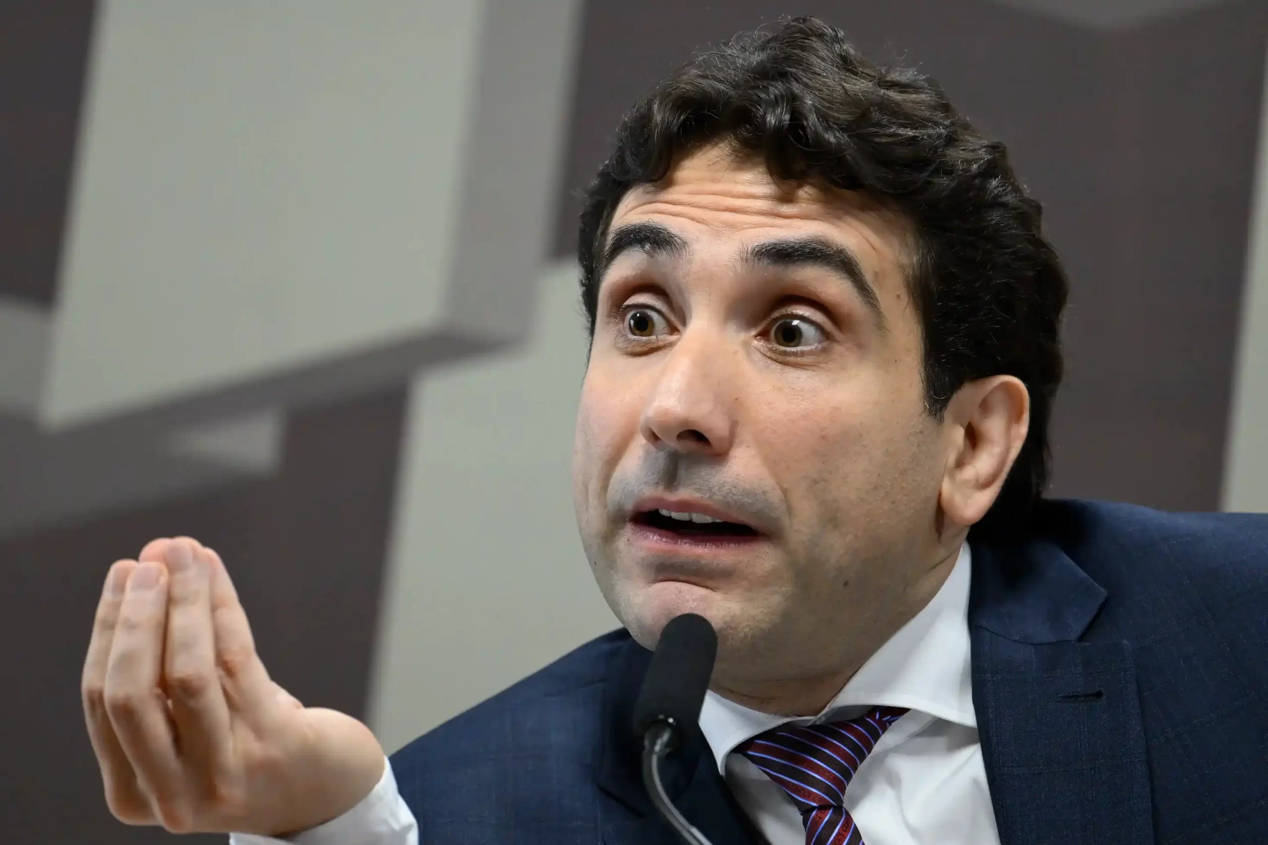 O presidente do Banco Central, Galípolo, falando em uma audiência com o braço estendido, defendendo o debate sobre a política monetária, mas alertando que o BC "não pode brigar com os dados".