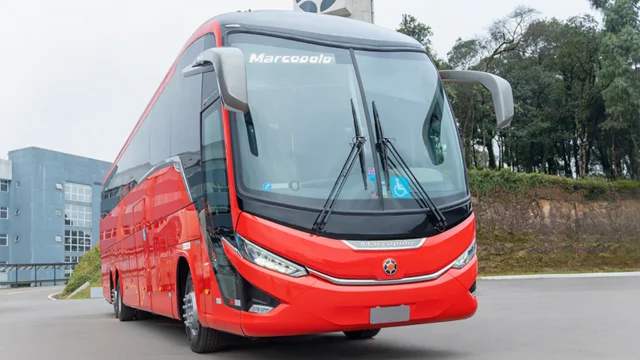 Vista frontal de um ônibus rodoviário vermelho da Marcopolo, simbolizando a previsão do BofA de uma alta de 40% para a ação (POMO4) após o início da cobertura.