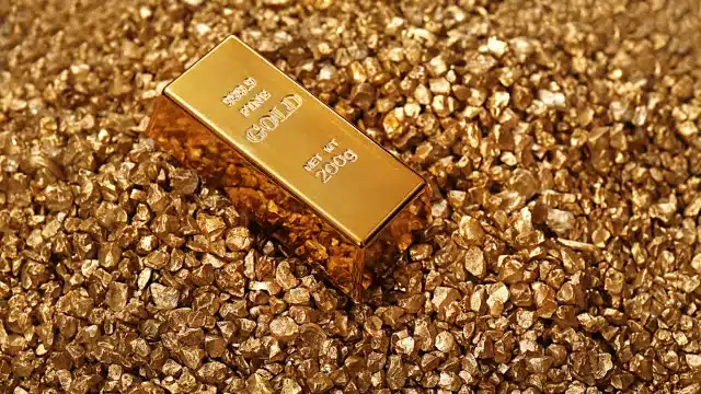 Barras de ouro empilhadas e reluzentes, representando a produção de metais preciosos da Aura Minerals e sua tese de investimento focada em crescimento e dividendos para 2026.