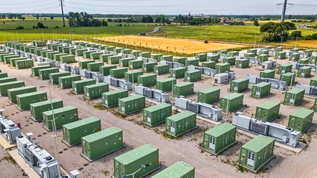 Vista aérea de um parque de baterias de armazenamento de energia (BESS) com diversas fileiras de containers verdes instalados em uma área aberta sob o sol, ilustrando a infraestrutura da Enel.