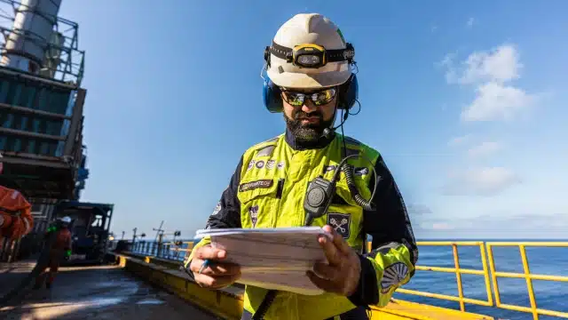 Funcionário da Prio olha ficha de produção em plataforma de petróleo